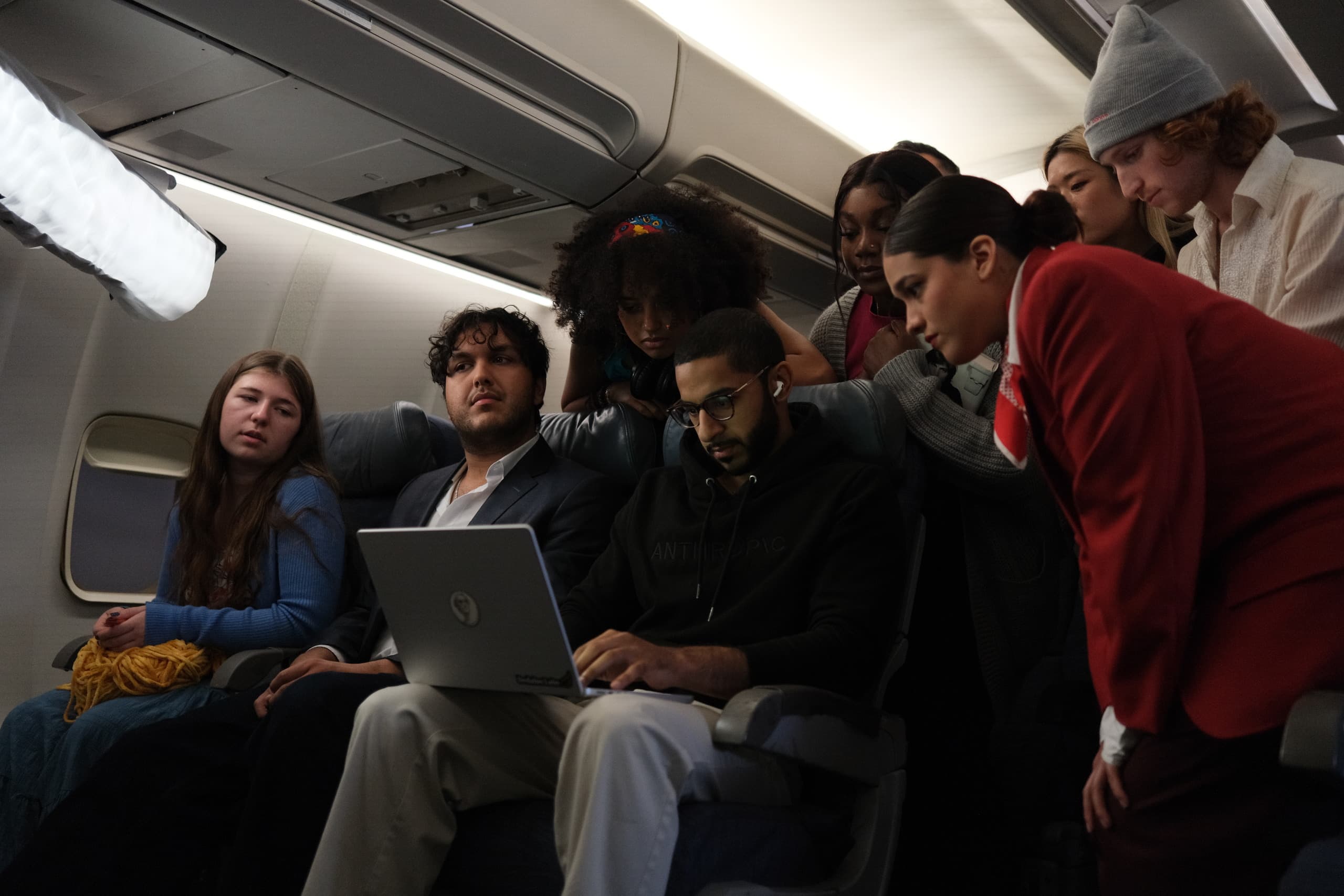 The crew gathered around a laptop on an aircraft cabin set